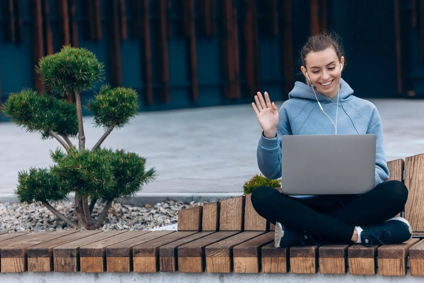 A girl wearing earphones waving during a video call.