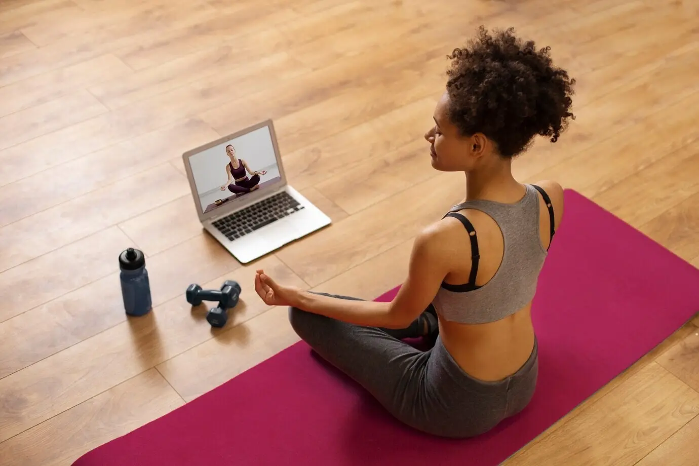 Full-body shot of a woman sitting on a yoga mat.